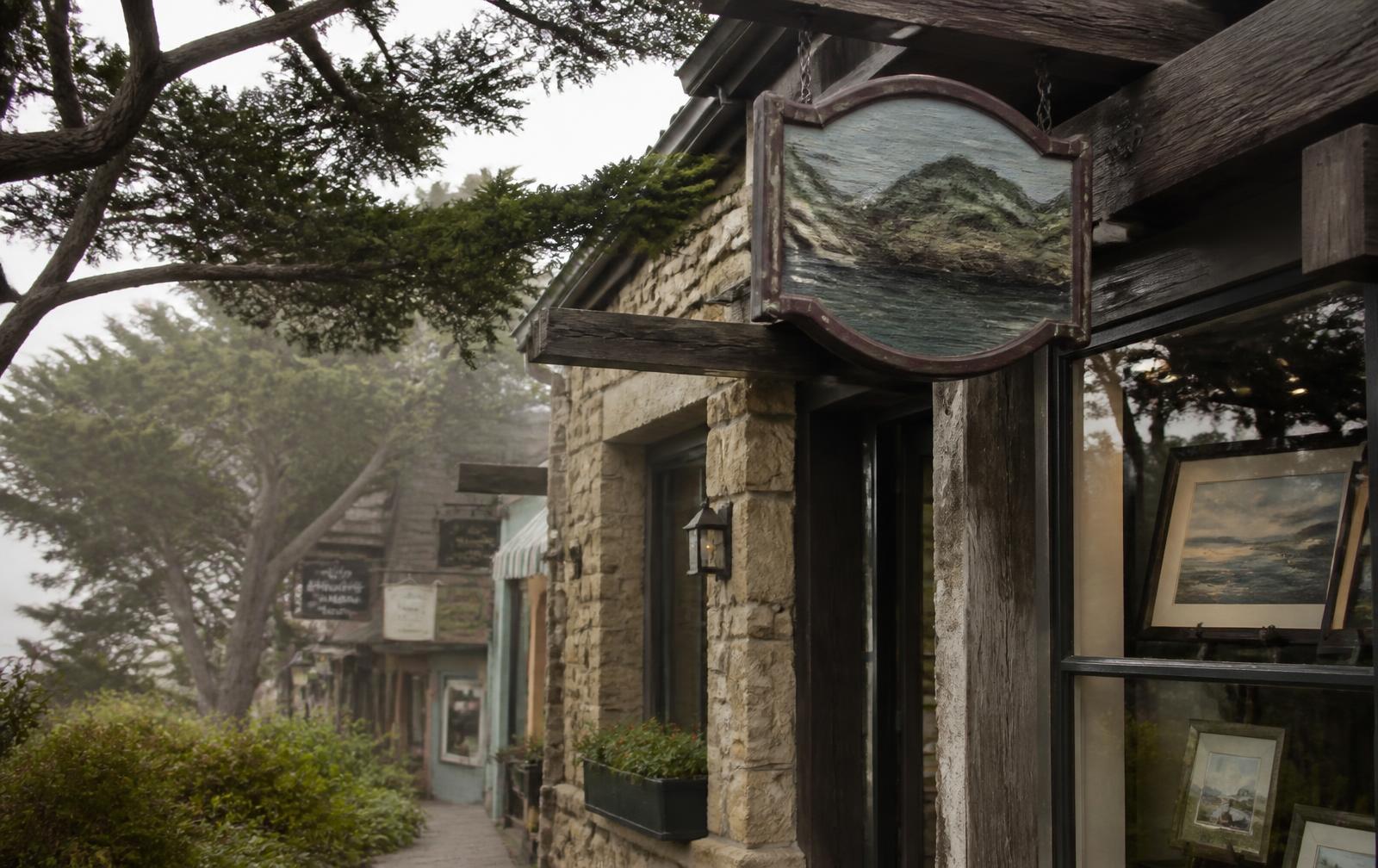 A stone and weathered-wood commercial storefront in Carmel-by-the-Sea on a foggy morning